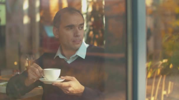 Homem bebe chá e olha pela janela com alegria — Vídeo de Stock