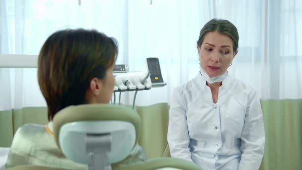 Доктор снимает маску во время разговора с пациентом — стоковое видео