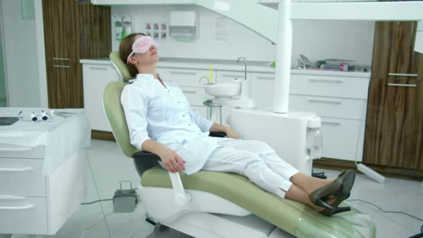Доктор расслабляется на стоматологическом стуле — стоковое видео