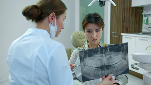 Dentista mostra a menina seus dentes em raio-x — Fotografia de Stock