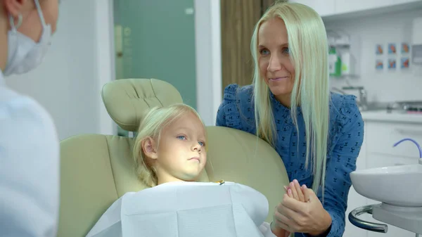 Moeder zit met haar dochter en praat met tandarts — Stockfoto
