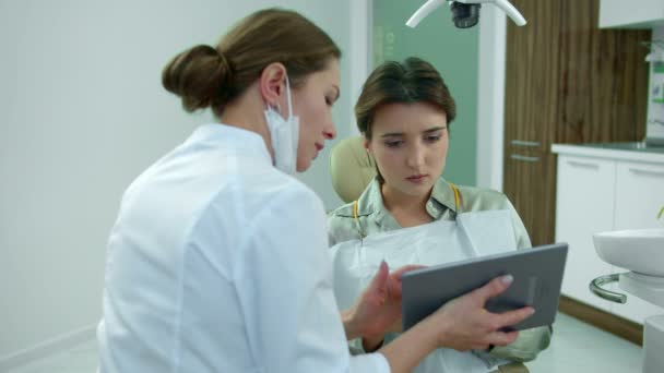 Zubař si promluví s pacientkou a ukáže jí něco na desce. — Stock video