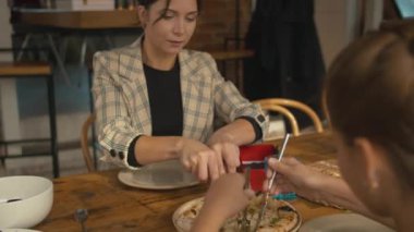 Anne kızıyla öğle yemeğinde pizza kesiyor.