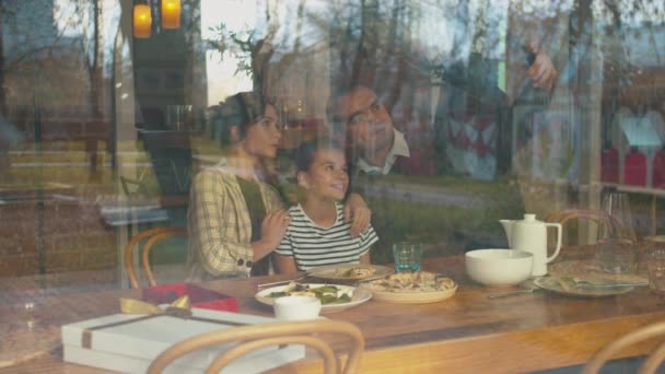 Föräldrar gör en selfie på telefon med dotter på café — Stockvideo