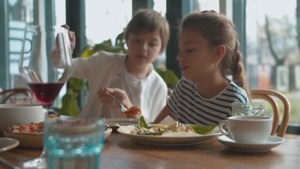 Anya és fia sajtot vesz egy tányérról, a lány pizzát eszik. — Stock videók