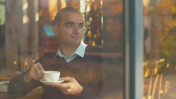 Человек пьет чай и смотрит в окно с радостью — стоковое фото