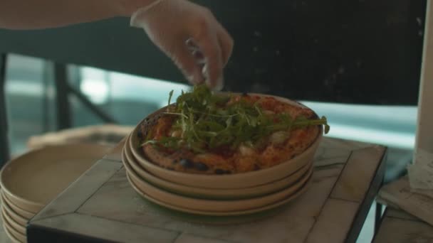 Chef zet arugula op pizza met zijn handen in latex handschoenen — Stockvideo