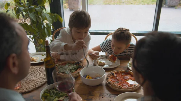 Top view, boy takes a food from a plate, girl eats pizza