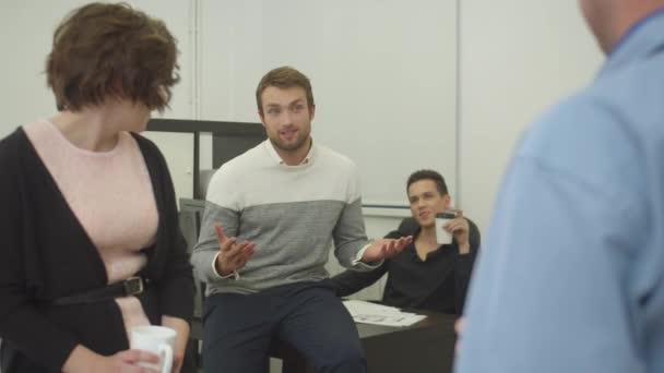 Jonge man vertelt een verhaal aan collega 's tijdens de pauze in het kantoor — Stockvideo