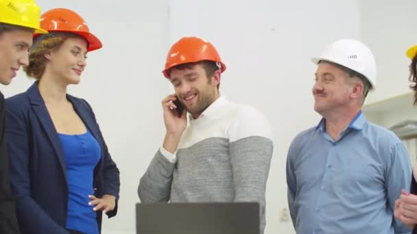Man in helmet talks on the phone during meeting with architects — ストック動画
