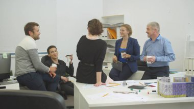 Meslektaşlar birbirleriyle konuşuyor ve tatilde kahve içiyorlar.