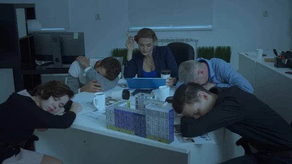 Μοντέλο του σπιτιού στο τραπέζι, οι συνάδελφοι κάθονται και κοιμούνται, γυναίκα προσπαθούν να εργαστούν — Φωτογραφία Αρχείου