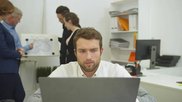 El hombre que trabaja en el ordenador portátil, sus compañeros de trabajo discutir esquema de apartement — Foto de Stock