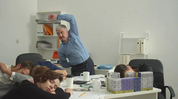 Mensen slapen en hun chef doet fysieke oefeningen op kantoor. — Stockfoto