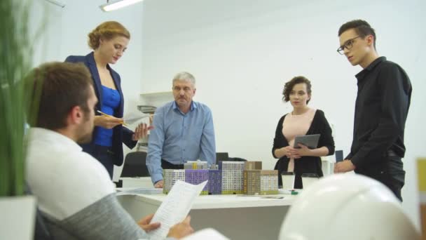 Зустріч в офісі, співробітники обговорюють щось з документами — стокове відео
