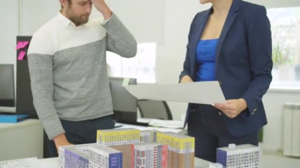 Інженер зі схемою в руці обговорити проект будинків з колегою по роботі — стокове відео