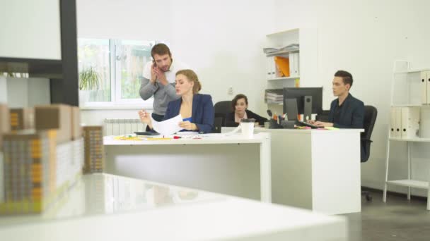 Homme parler au téléphone, collègues de travail l'aider à montrer des schémas d'appartements — Video