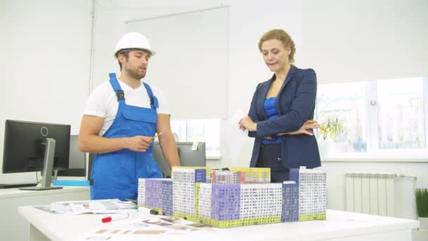 Constructor hablar con la mujer, discuten proyecto de casas — Vídeo de stock