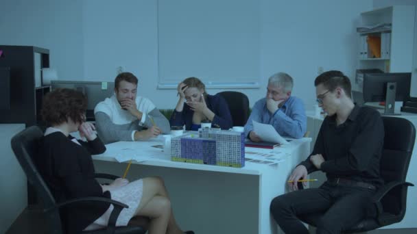 Tired engineers sit at a table and yawn — Stock Video