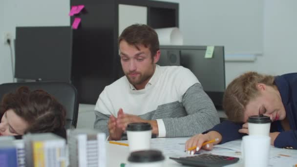 Unavený muž sedí u stolu a tleská, aby mohl pokračovat v práci — Stock video