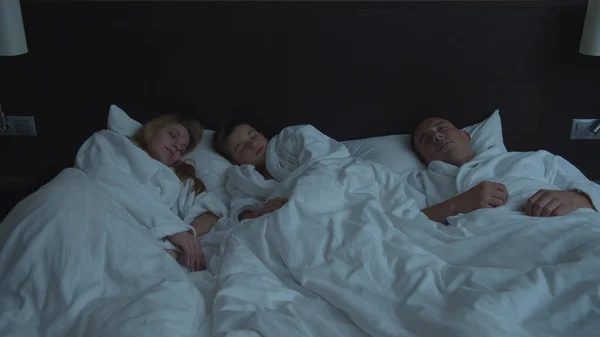 Familia en el hotel, pequeño hijo dormir con los padres en una cama — Foto de Stock