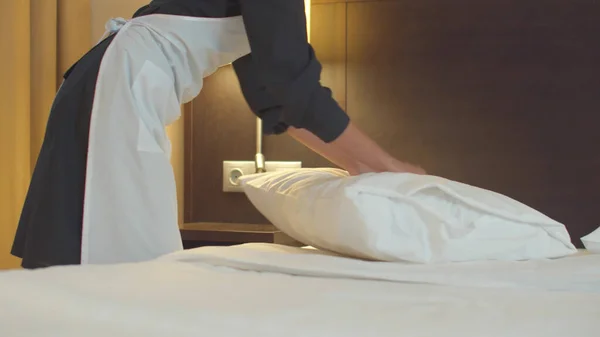 Pokojówka pościelić łóżko i najlepiej poduszkę w pokoju hotelowym — Zdjęcie stockowe