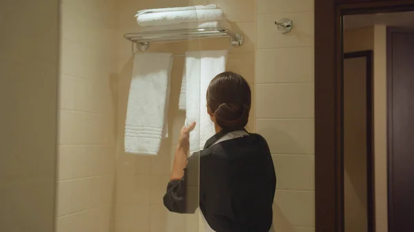 Pokojówka w mundurze położyć ręczniki na wieszaku w łazience w hotelu — Zdjęcie stockowe