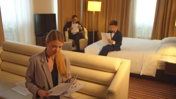 Άνδρας, αγόρι και γυναίκα με κοστούμια κάθονται και κοιτάζουν τα έγγραφα στο δωμάτιο του ξενοδοχείου — Φωτογραφία Αρχείου