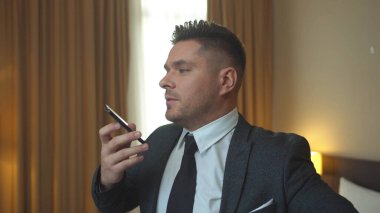 Adam ceketini giydi ve otel odasında telefonla konuştu.