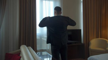 Adam otel odasında ceket giydi, telefonu aldı ve dışarı çıktı.