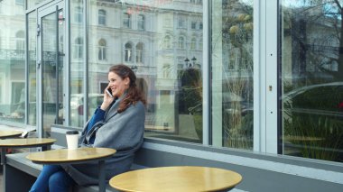 Gri battaniyeli kız dışarıda otur ve telefonda konuş.