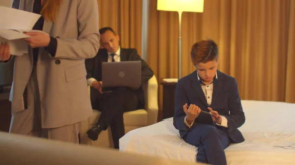 Мужчина в работе на ноутбуке, маленький мальчик сидит с планшетом, женщина смотрит на документы в руке — стоковое фото