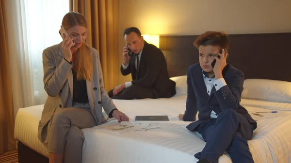 Family talk on phones in hotel room