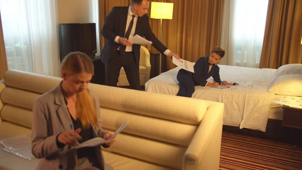 Άνδρας, αγόρι και γυναίκα με κοστούμια εργάζονται με έγγραφα στο δωμάτιο του ξενοδοχείου — Φωτογραφία Αρχείου
