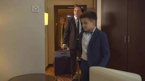 Мама, папа и сын вошли в гостиничный номер с сумками — стоковое фото