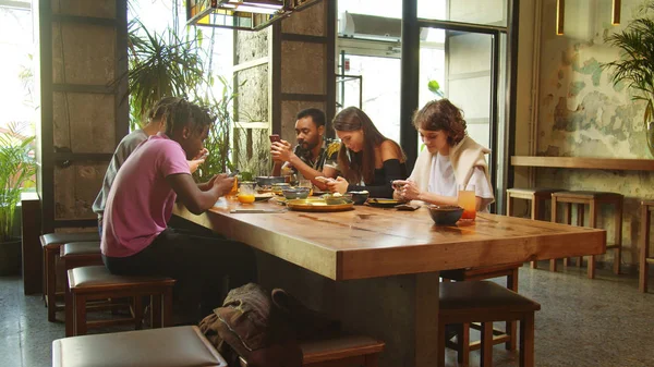 Вид сбоку, друзья сидят в кафе, сидят с телефонами в руках — стоковое фото