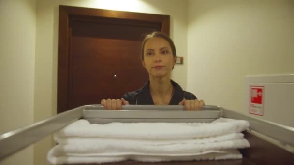 Домохозяйка проходит по коридору отеля с оборудованием для уборки — стоковое видео