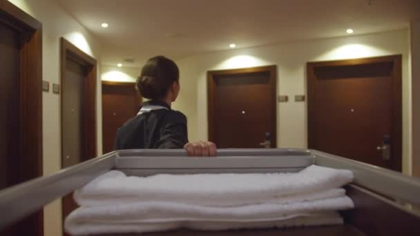 Back view, housemaid go through corridor of hotel with cleaning equipment — Stock Video