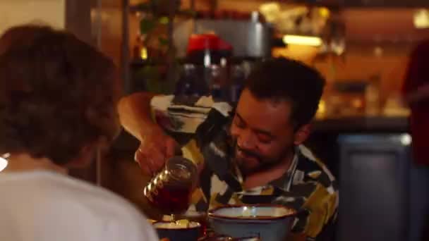 Homme et femme assis à une table dans un café, l'homme verser le thé dans la tasse — Video