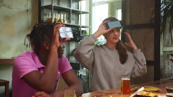 Vrienden zitten in een café, spelen woordspelletjes met telefoons, vrouw legt een woord uit — Stockvideo