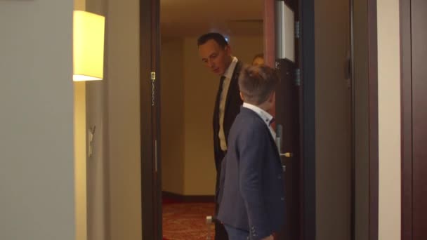 Öltönyös emberek jöttek a hotelszobába táskákkal. — Stock videók