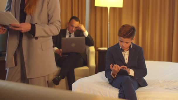 Мужчина в работе на ноутбуке, маленький мальчик сидит с планшетом, женщина смотрит на документы в руке — стоковое видео