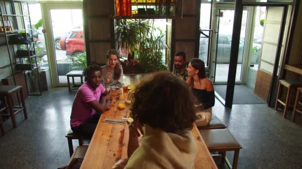 Компанія друзів зустрічається в кафе, вони їдять їжу і грають в походи — стокове відео