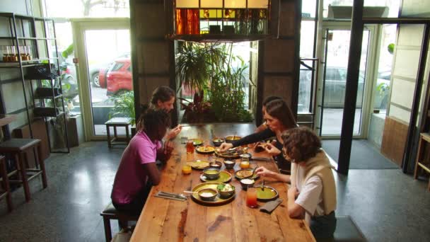 Compañía de amigos se reúnen en un café, se sientan y comen comida — Vídeos de Stock