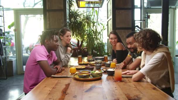 Gruppe multikultureller Freunde sitzt beim Mittagessen und spricht — Stockvideo