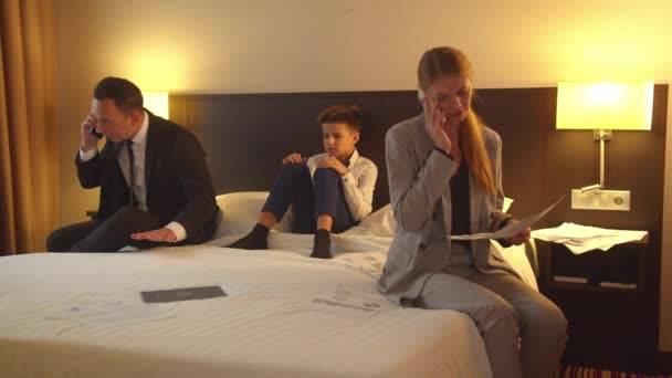 男と女はホテルの部屋で電話で話し少年はベッドに座って聞いて — ストック動画