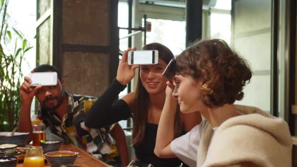 Grupo de amigos sentar em um café, jogar em jogo de palavras com telefones, menina explicar uma palavra — Vídeo de Stock