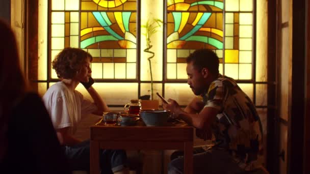 Άντρας και γυναίκα κάθονται σε ένα τραπέζι σε ένα καφέ, άντρας κάθεται στο τηλέφωνο, γυναίκα μιλάει στο τηλέφωνο — Αρχείο Βίντεο
