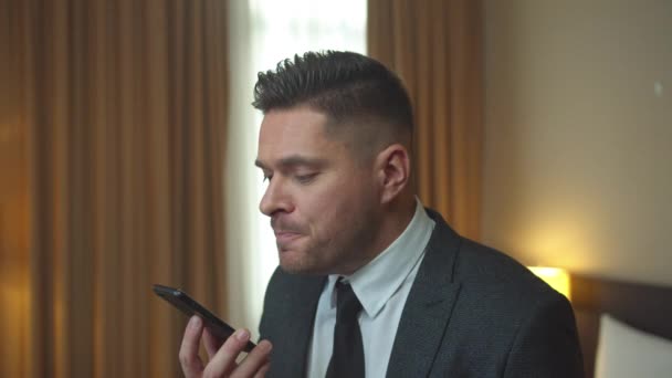 Mężczyzna w kurtce rozmawiać przez telefon nerwowo w pokoju hotelu — Wideo stockowe