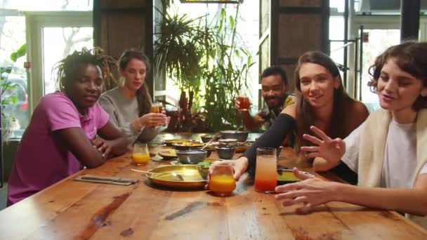Les gens s'assoient dans un café, ils parlent à la caméra et offrent à manger et à boire — Video